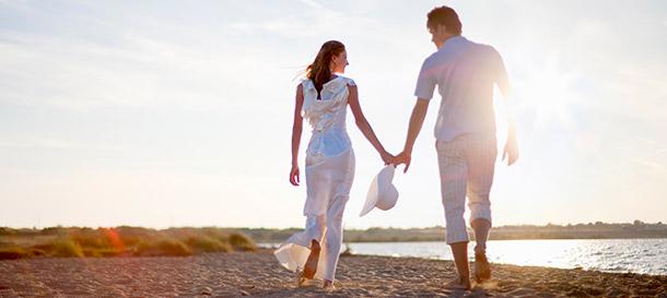A newlywed couple walks along a beach