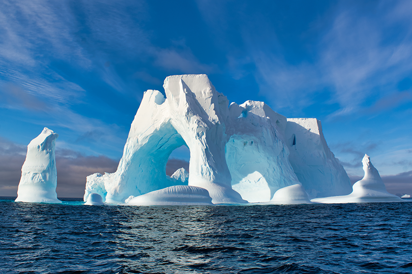 Beautiful blue waters and skies surround a massive glacier in Antarctica